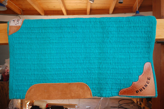 Hand-woven turquoise saddle blanket with hand tooled leather name plate.