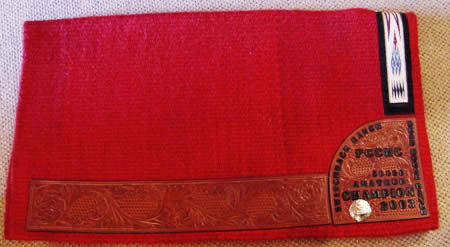 A hand-made Brown Cow Saddle Blanket with hand-tooled Wear-leather and a hand-tooled award plaque